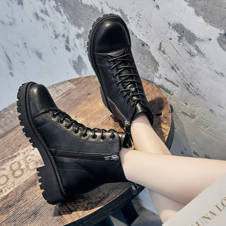 Schwarze Lederstiefel mit Reißverschluss und Schnürung auf Holztisch, modisch und robust.