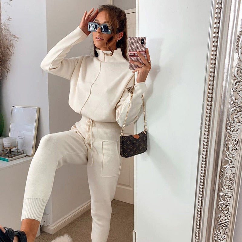 Frau in cremefarbenem Strick-Set mit Sonnenbrille und Designer-Handtasche im Spiegel-Selfie.