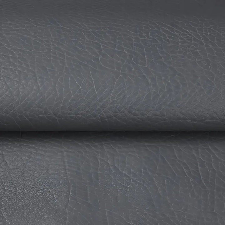 Detail šedé zrnité textury záplaty, materiál je přehnutý do záhybu 8