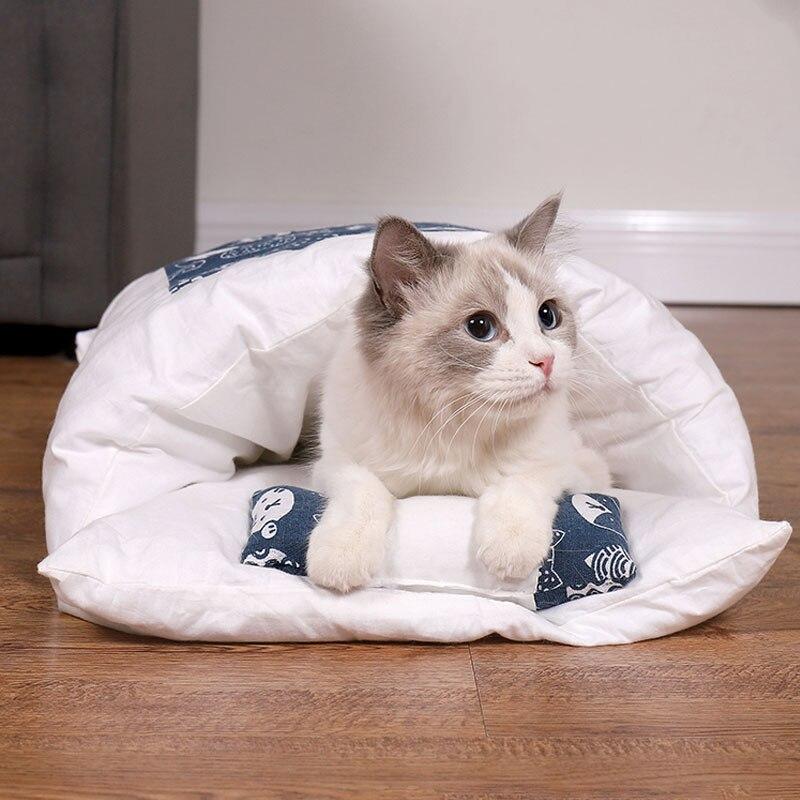 Katze in weißem, blau gemustertem Katzenbett auf Holzboden, gemütlich und entspannt.