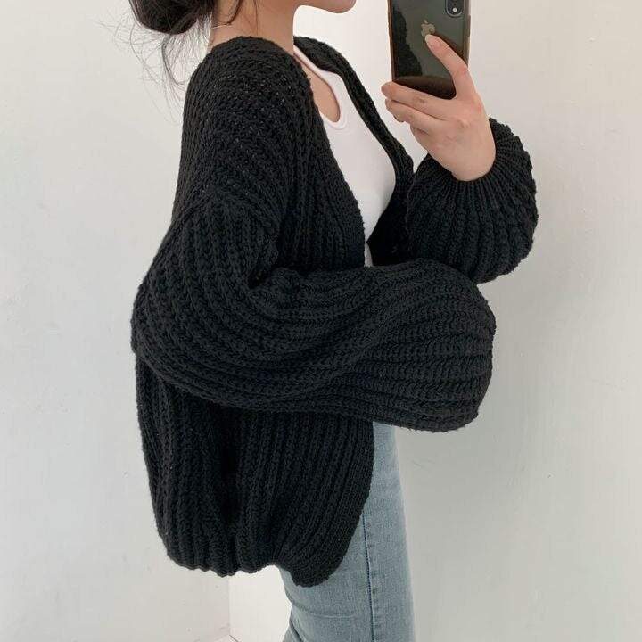 Frau trägt schwarzen Strickcardigan, Oversize, grob gestrickt, modisch, gemütlich, Herbstmode.