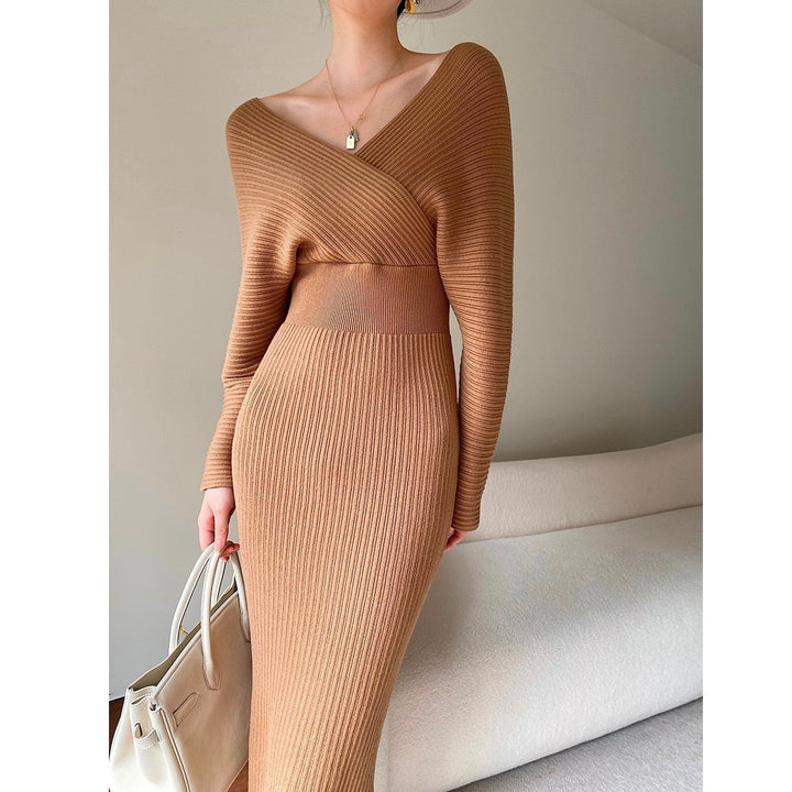 Frau in braunem Strickkleid mit V-Ausschnitt, hält beigen Lederhandtasche, modisch elegant.