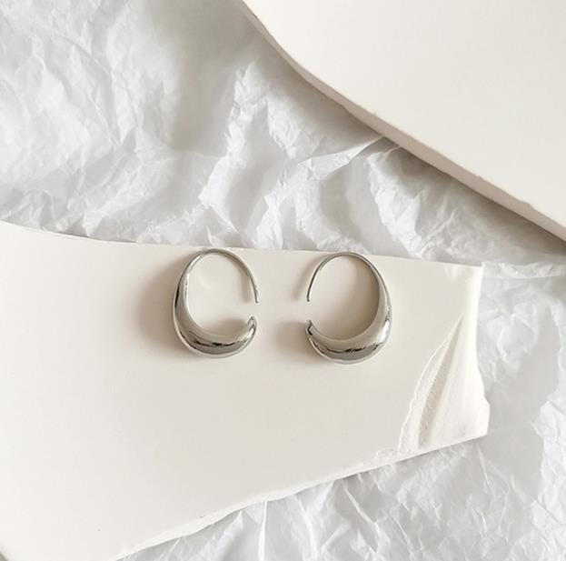 Silberne Creolen Ohrringe auf weißem Hintergrund, minimalistisches Schmuckdesign.