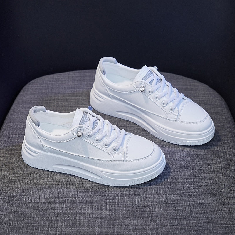 Weiße Sneaker aus Leder, modisch, bequem, für Damen und Herren, auf grauem Hintergrund.