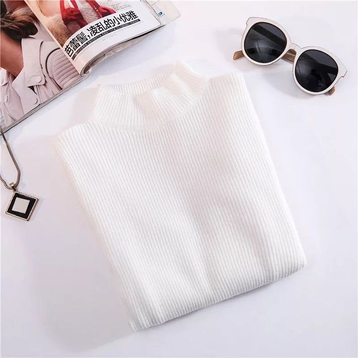 Weißer Rollkragenpullover aus Strick, Damenmode, elegant, Herbst-Winter, neben Sonnenbrille.