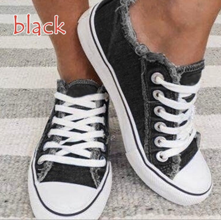 Schwarze Canvas-Sneaker mit weißen Schnürsenkeln, lässiger Stil, Damenmode, auf Teppich.