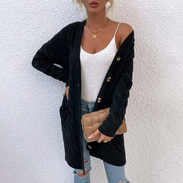 Frau in schwarzem Strickcardigan mit Knöpfen, weißem Top, blauer Jeans und beiger Clutch.