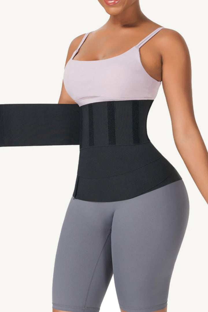 Frau trägt schwarzen Taillenstützgürtel, Sportbekleidung, Figurformung, Fitness, Bauchweg.
