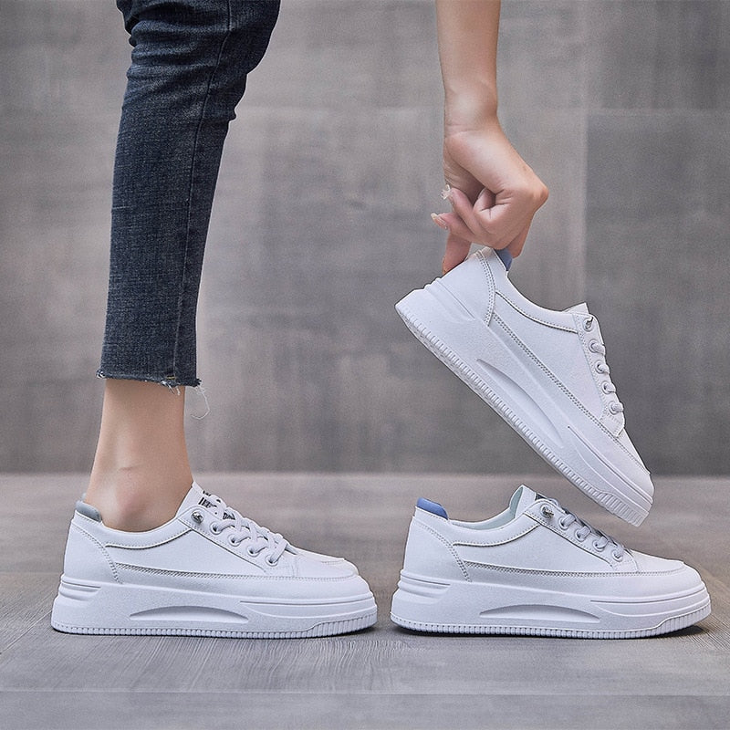Weiße Sneaker Damen, modisch, bequem, Freizeit, Jeans, grauer Hintergrund.