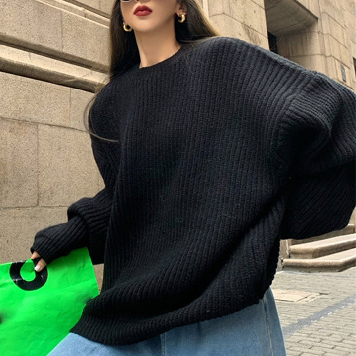Frau in schwarzem Strickpullover, hält grüne Tasche, modisch, urbaner Hintergrund.
