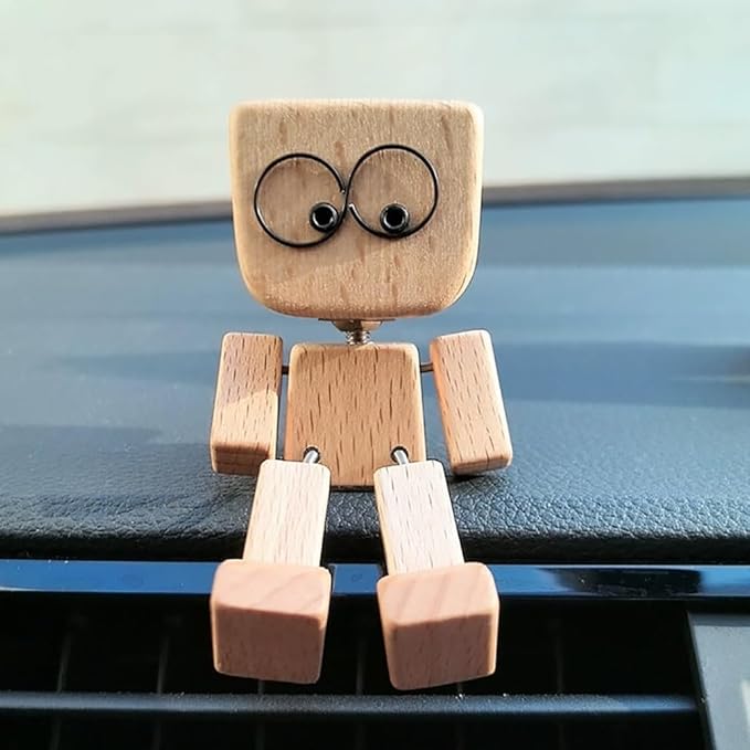 Dřevěná figurka z předu s širokýma očima sedí na palubní desce, nohy visí dolů. 4