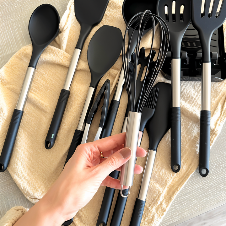 Küchenutensilien-Set aus Edelstahl und Silikon, schwarz, auf beigem Tuch.