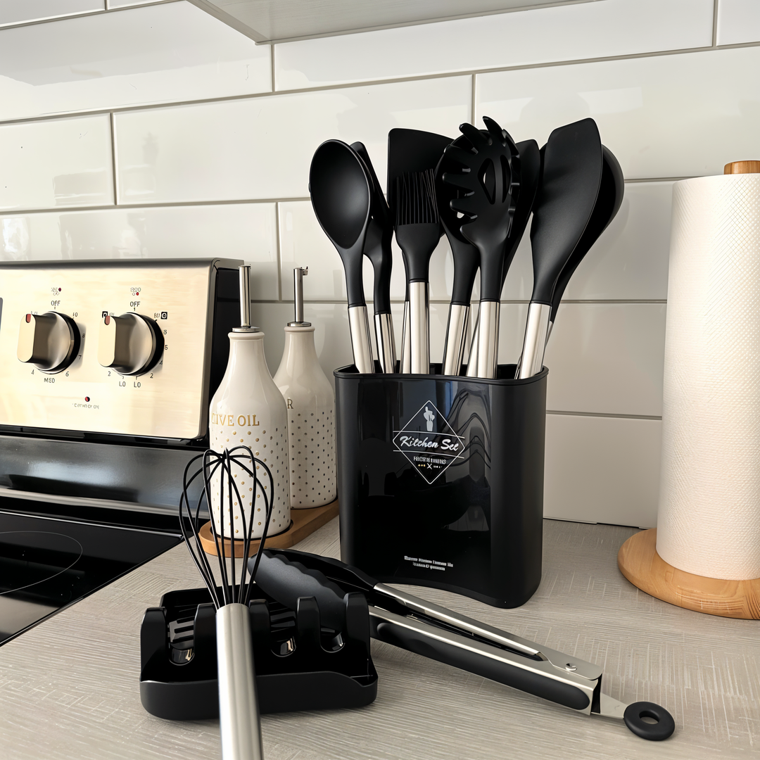 Schwarzes Küchenutensilien-Set aus Edelstahl, Löffel, Schneebesen, Zange, auf Arbeitsplatte.