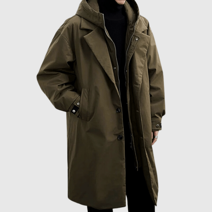 Olivově zelená dlouhá pláštěnka s kapucí na modelovi, zblízka na límec, knoflíky a zip, ruka v kapse 1