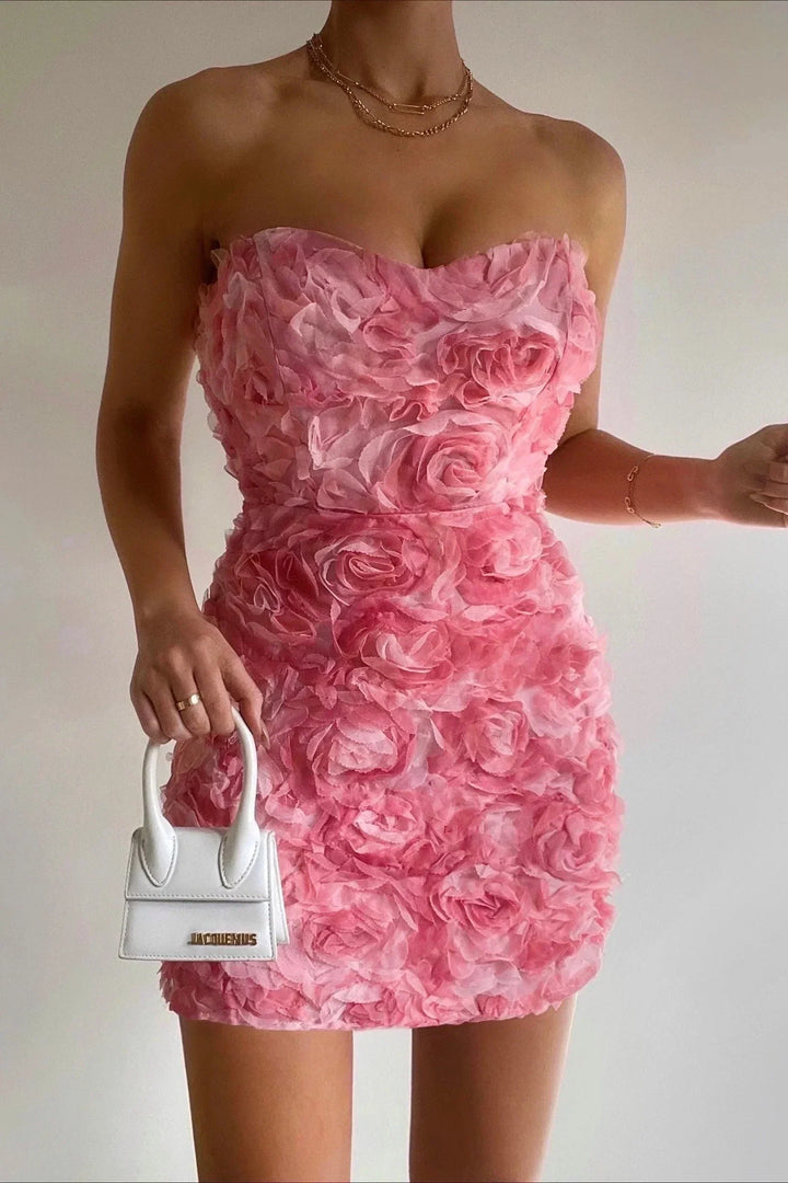 Frau im rosa Blumenkleid mit weißer Mini-Handtasche, elegantes Abendoutfit.