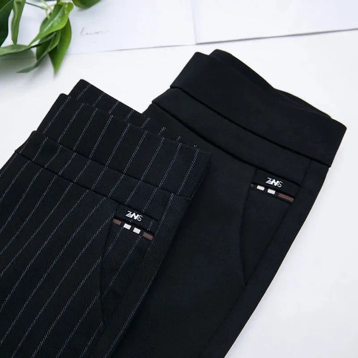 Zwei schwarze Anzughosen, eine mit Nadelstreifen, auf weißem Hintergrund, elegante Herrenmode.