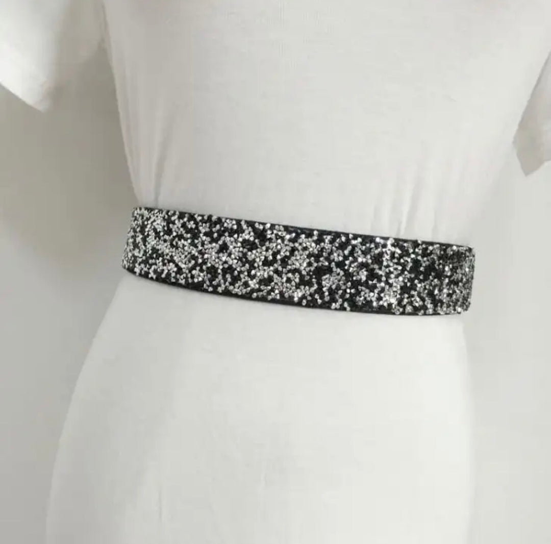 Schwarzer Pailletten-Gürtel auf weißem Kleid, modisches Accessoire, glänzend, elegant.