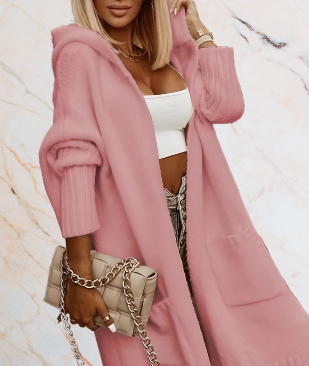 Frau in rosa Strickjacke mit Kapuze, weißem Top, beiger Tasche, modisch, elegant.
