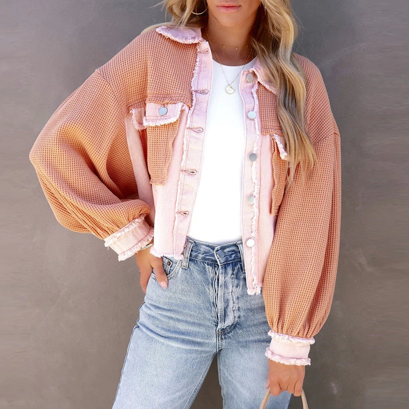 Frau trägt rosa-orange Strickjacke, weiße Bluse, Jeans; modische Damenbekleidung.