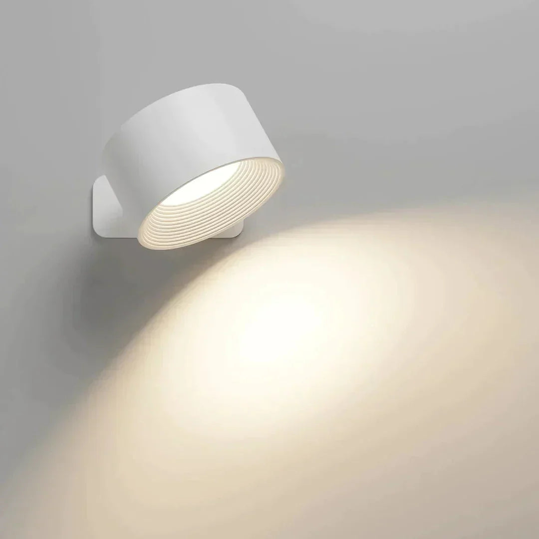 Bílá lampa se skloněnou hlavou a měkkým kuželem světla na šedé stěně 8