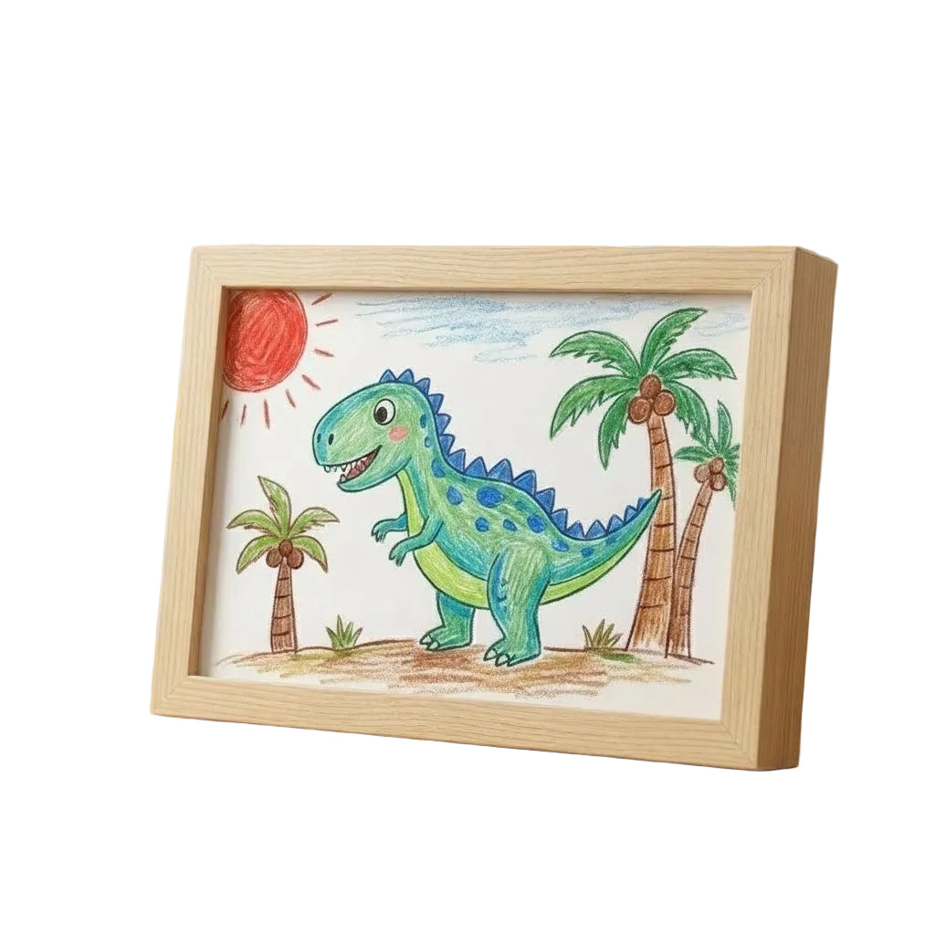 Světlý dřevěný rám s dětskou pastelkovou kresbou zeleného dinosaura mezi palmami a sluncem, vyfocený na bílém pozadí z boku. 1
