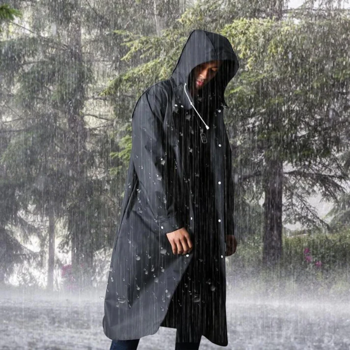 Mann in langer, schwarzer Regenjacke mit Kapuze im Regen stehend, Outdoor-Bekleidung.