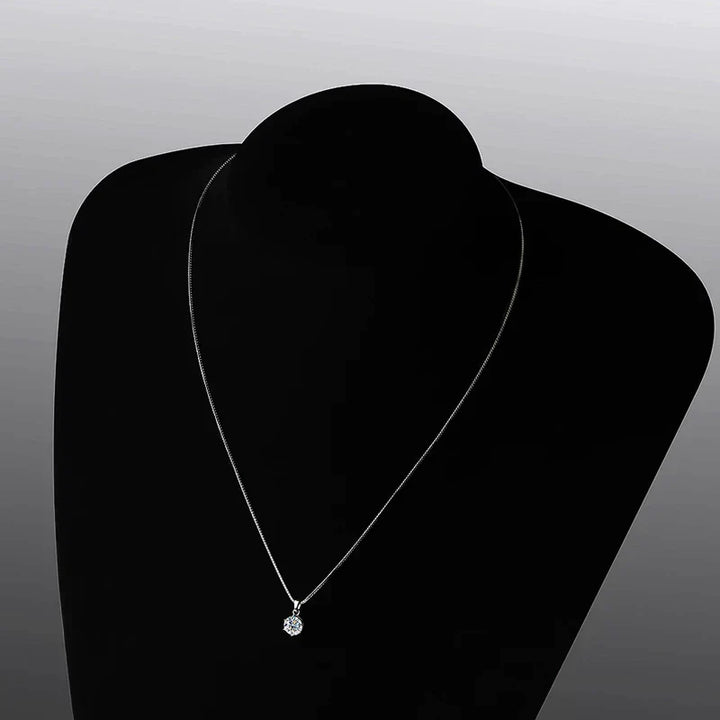 Silberne Halskette mit rundem Diamantanhänger auf schwarzem Hintergrund, eleganter Schmuck.
