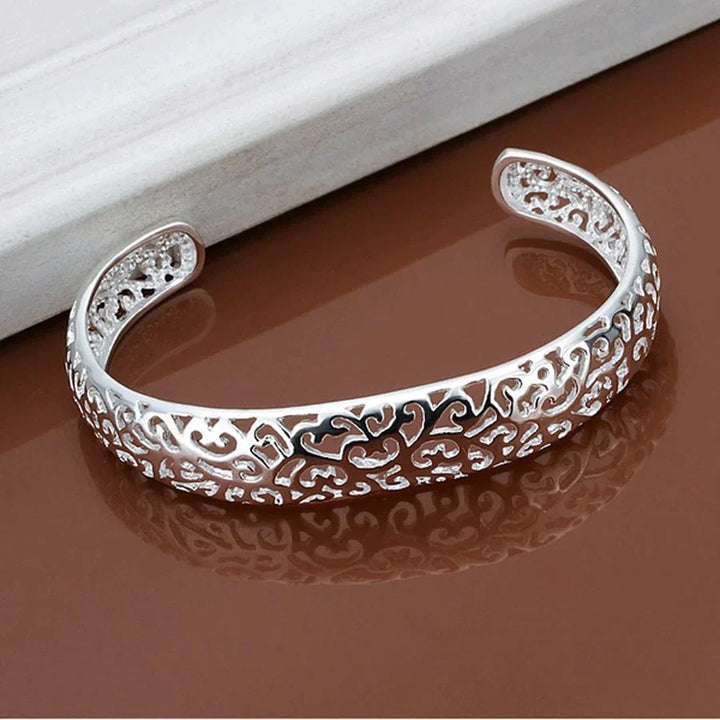 Silbernes Armband mit filigranem Muster, offenes Design, Schmuck für Damen, elegant und stilvoll.