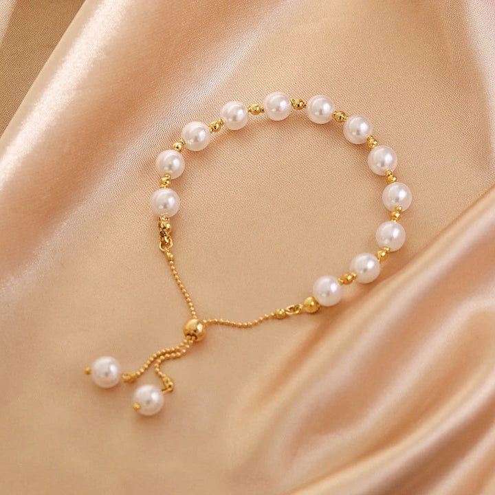 Perlenarmband mit goldenen Akzenten auf beigem Satin, eleganter Schmuck, verstellbar.