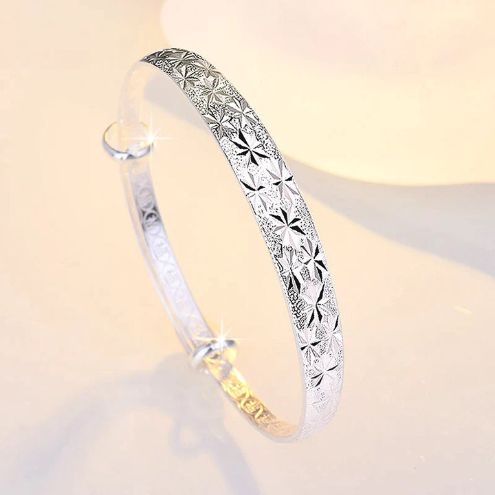 Silberarmreif mit Sternmuster, glänzend, elegantes Schmuckstück für Damen, modisches Accessoire.