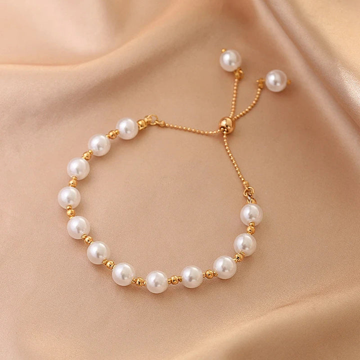 Perlenarmband mit goldenen Akzenten auf beigem Stoff, eleganter Schmuck, verstellbar.