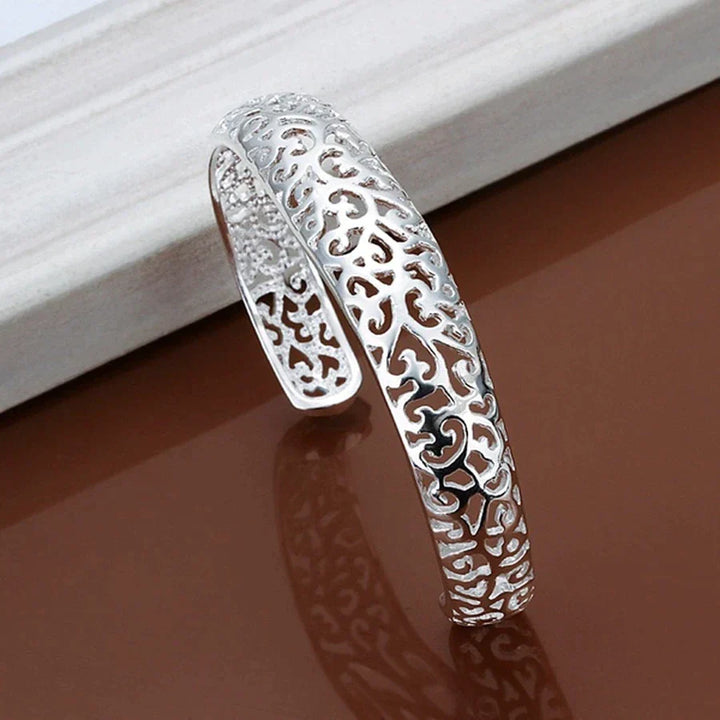Silberarmreif mit filigranem Muster, elegantes Schmuckstück, Damenarmband, modisches Accessoire.