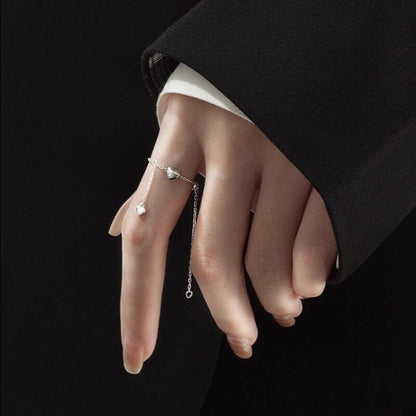 Silberner Damenring mit Kette und Herzanhänger, elegantes Schmuckdesign, minimalistisch.