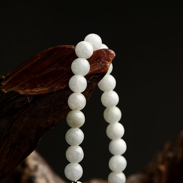 Weiße Jade-Perlenkette auf Holz, eleganter Schmuck, Naturstein, Nahaufnahme.