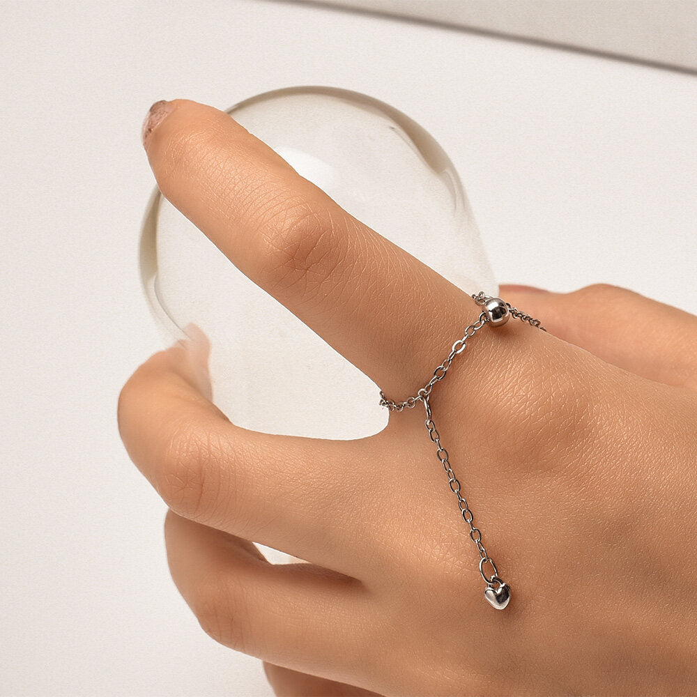 Silberner Kettenring mit Herzanhänger, eleganter Schmuck für Damen, modisches Accessoire.