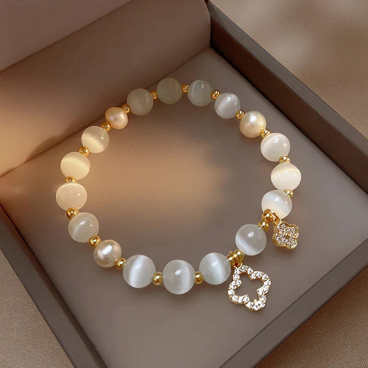 Perlenarmband mit goldenen Akzenten und Blumenanhänger, eleganter Schmuck, Geschenkidee.