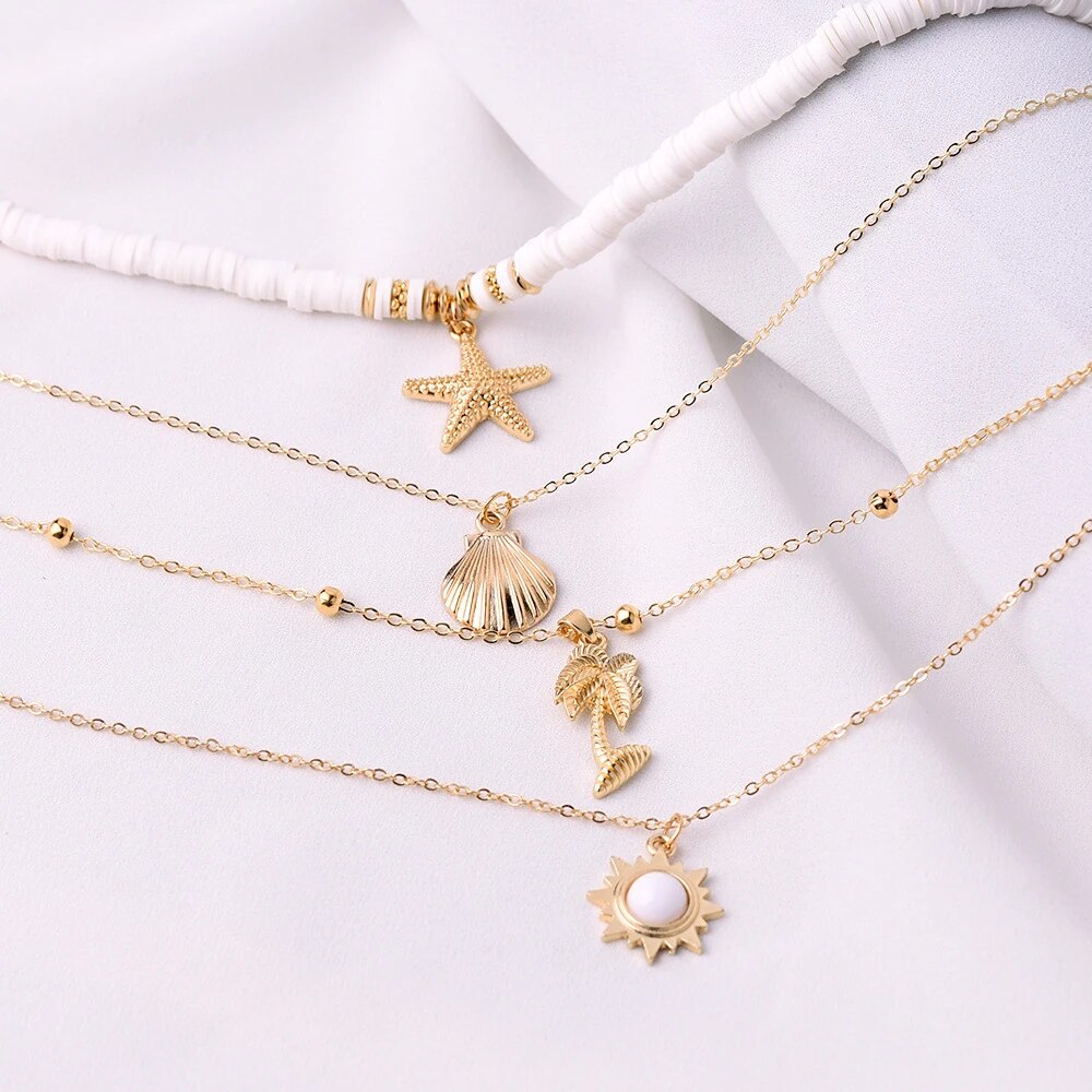 Goldene Halsketten mit Muschel- und Sternanhängern auf weißem Hintergrund, Modeschmuck.