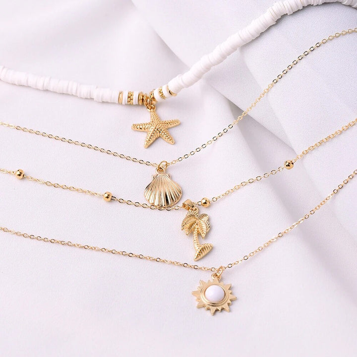 Goldene Halsketten mit Muschel- und Sternanhängern auf weißem Hintergrund, Modeschmuck.