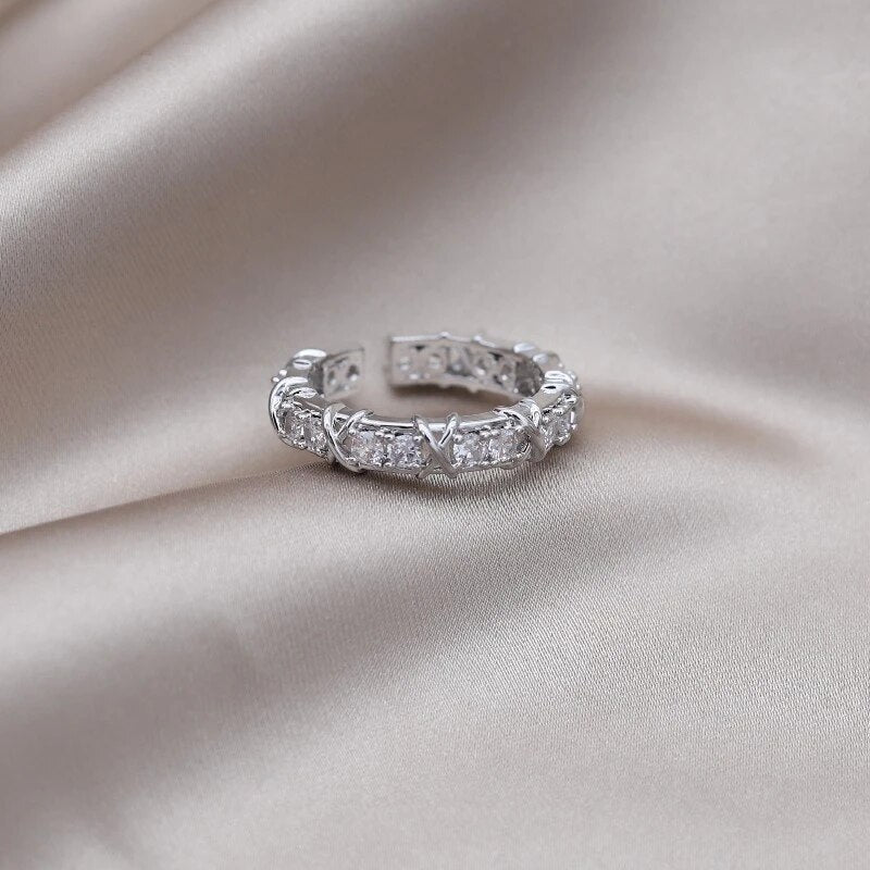 Silberner Ring mit Zirkonia-Steinen auf beigem Satin, eleganter Schmuck, Damenring, Geschenkidee.