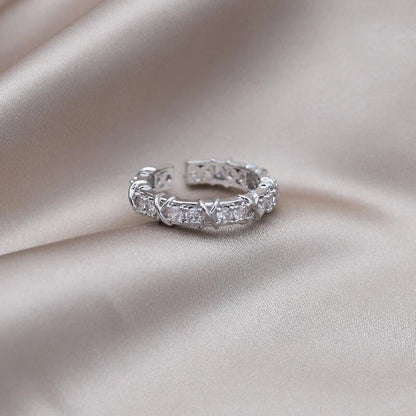 Silberner Ring mit Zirkonia-Steinen auf beigem Satin, eleganter Schmuck, Damenring, Geschenkidee.