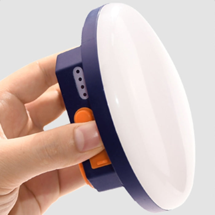 Hand hält tragbare LED-Lampe, rund, weiß, blau, mit Schalter, für Camping und Outdoor.