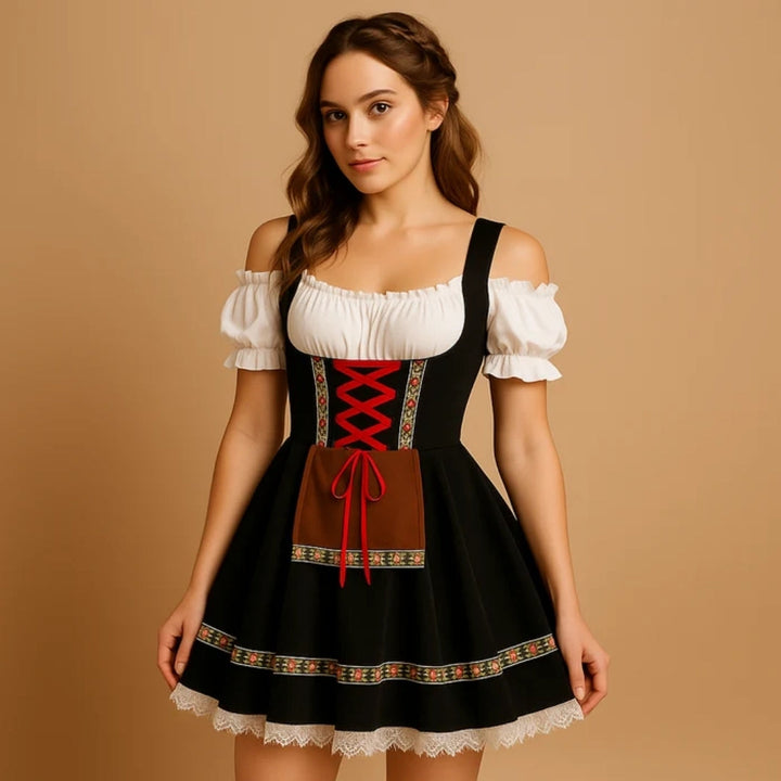 Modelka v černých dirndl šatech s červeným šněrováním, hnědou kapsou, květovanou stuhou na sukni, bílým krajkovým lemem a copánkem ve vlasech. 7
