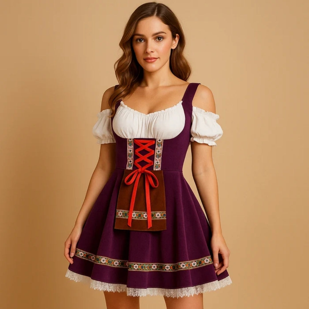 Modelka ve fialových dirndl šatech s odhalenými rameny, červeným šněrováním, hnědou kapsou se vzorovanou stuhou a krajkovým lemem sukně. 2