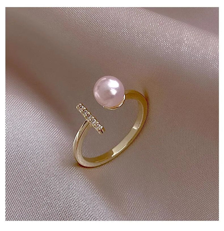 Goldener Ring mit rosa Perle und Diamanten auf Seidenstoff, eleganter Schmuck, luxuriöses Design.