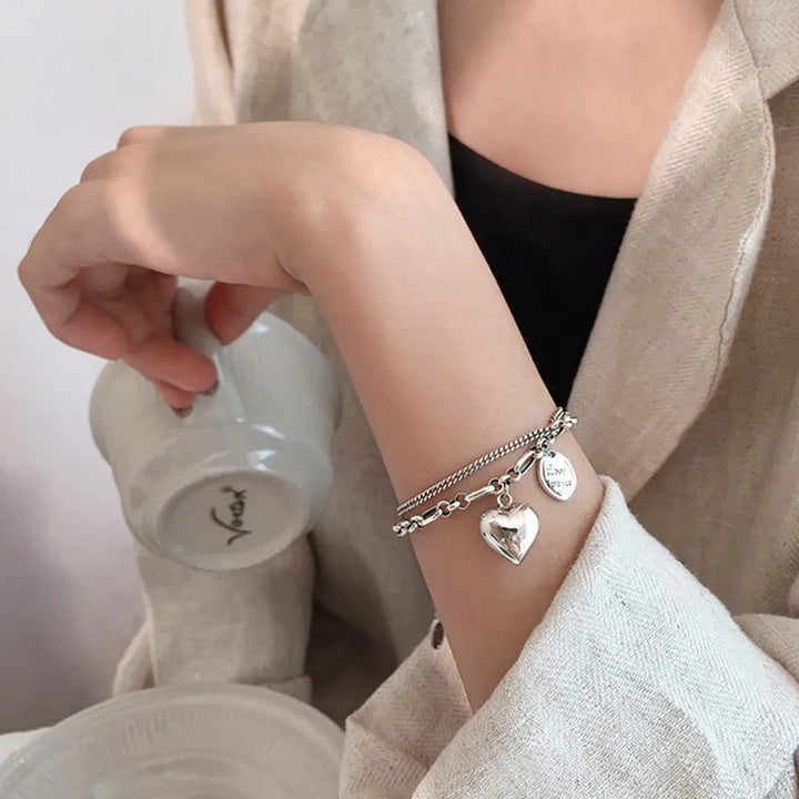Silberarmband mit Herzanhänger, Damenmode, elegantes Schmuckdesign, Geschenkidee.