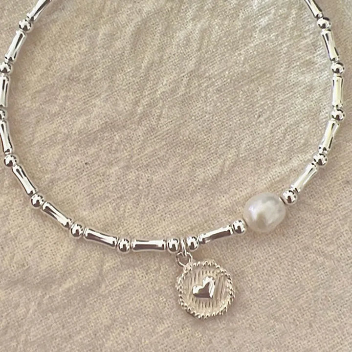 Silberarmband mit Perle und Herzanhänger, elegantes Schmuckdesign, Damenaccessoire.
