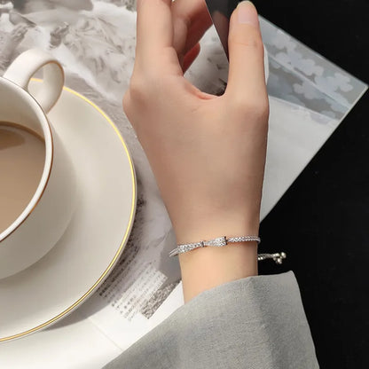 Silbernes Armband mit Strasssteinen an Hand, neben Kaffeetasse und Zeitschrift.