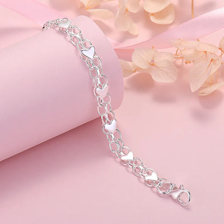 Silberarmband mit Herzanhängern, Damen, romantisches Schmuckdesign, Geschenkidee.