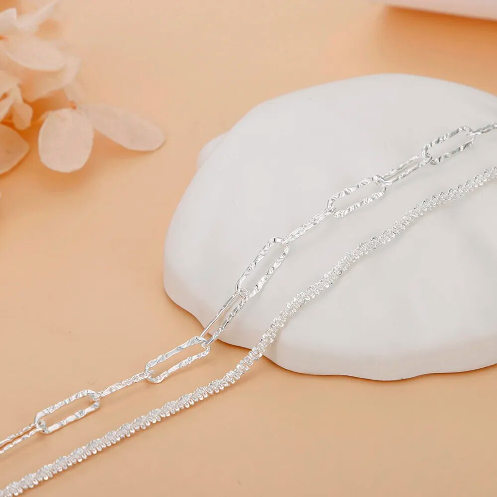 Silberne Halskette auf weißem Hintergrund, elegantes Schmuckdesign, modisches Accessoire.