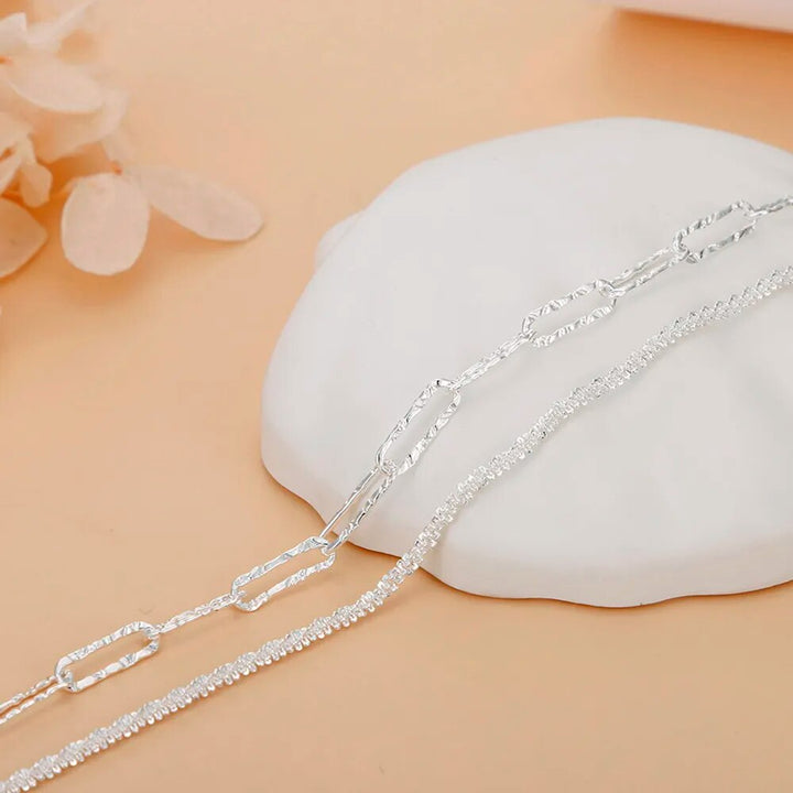 Silberne Halskette auf weißem Hintergrund, elegantes Schmuckdesign, modisches Accessoire.